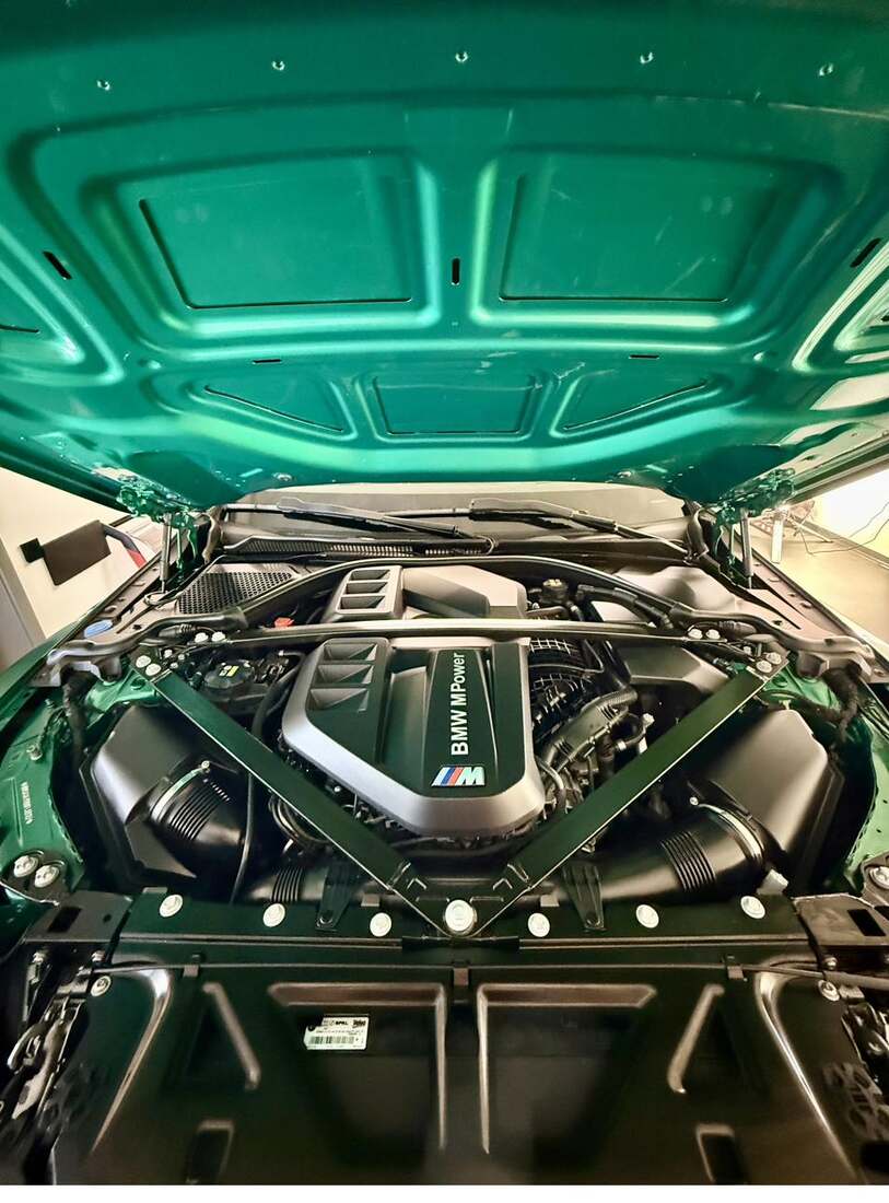 Geöffnete Motorhaube eines BMW M3 in Grün