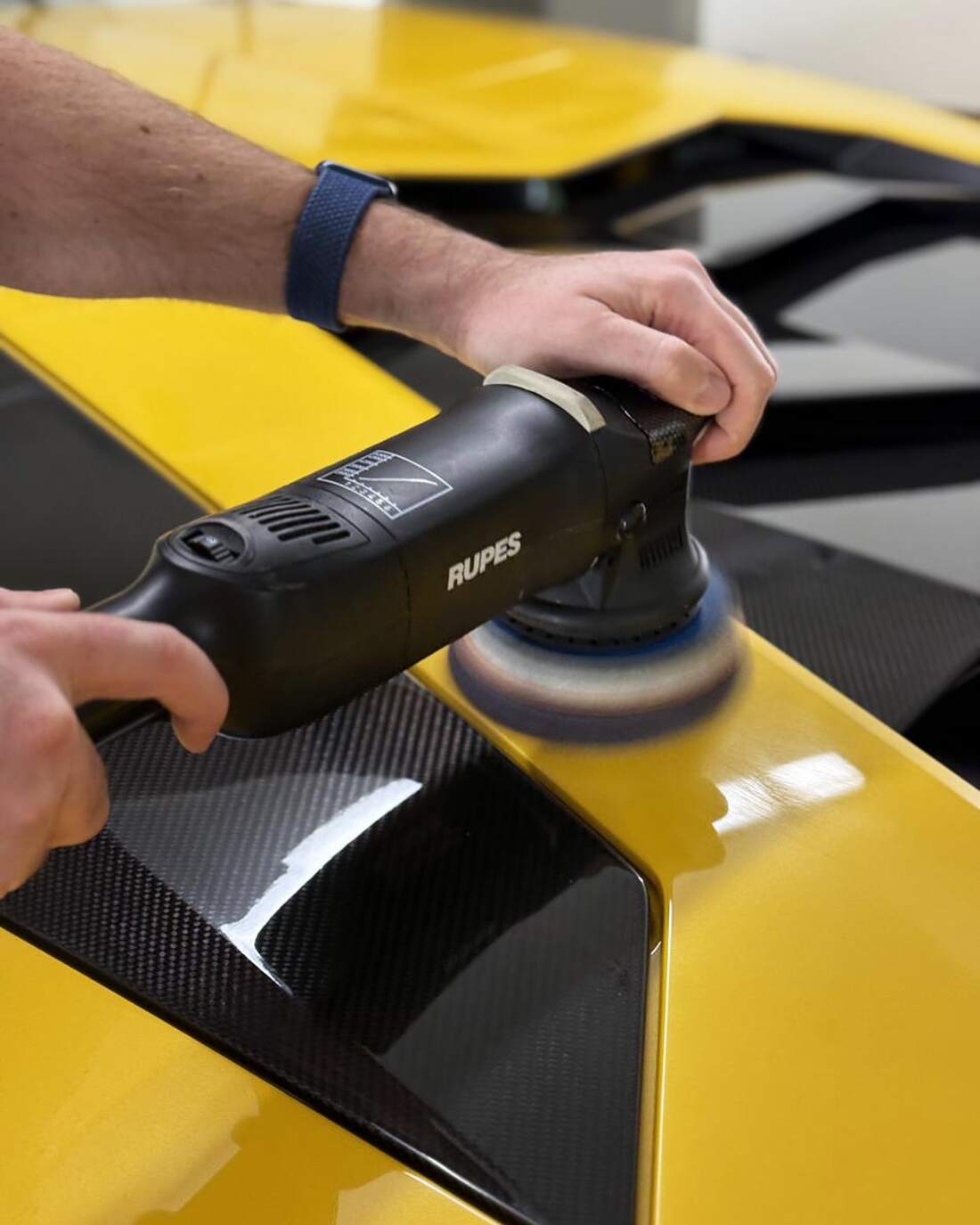 Poliermaschine in den Händen, Nahaufnahme auf gelbem Lamborghini