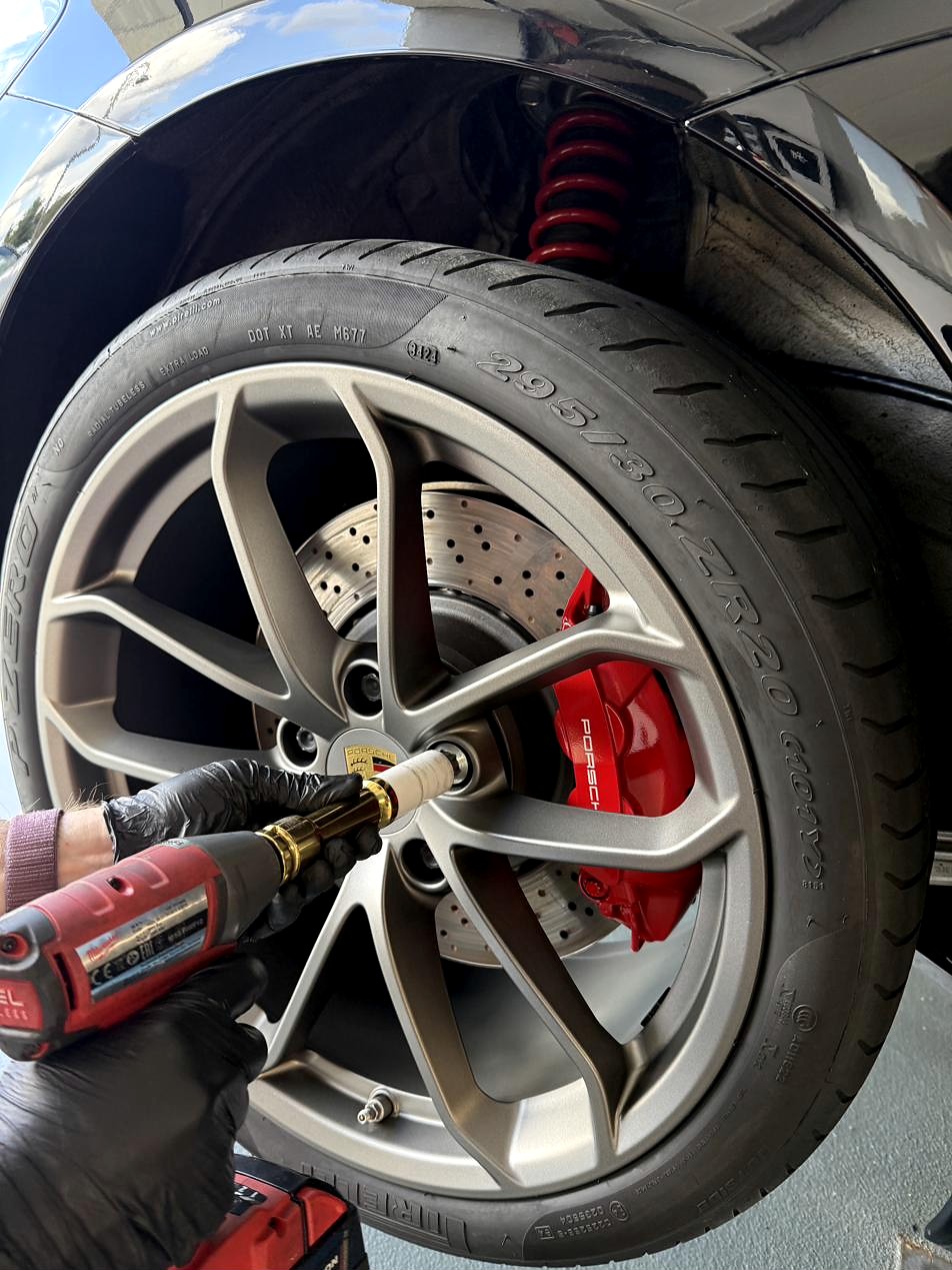Radmontage mit Schlagschrauber am Porsche mit rotem Bremssattel