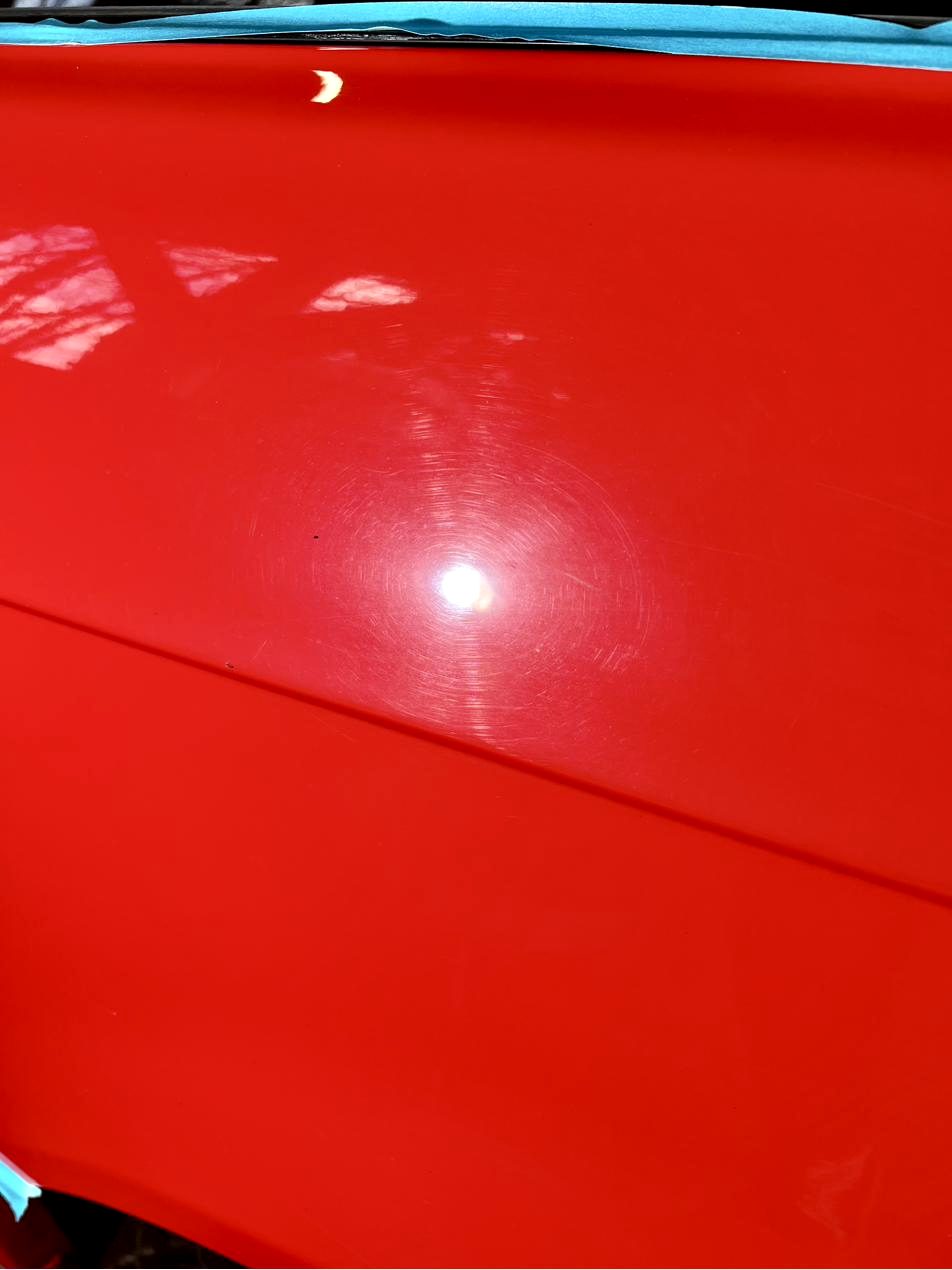 Swirls and wash marks under point light on red paint